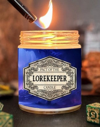 A lit blue glass jar candle with a decorative silver label reading 'Pact of the Lorekeeper Candle,' shown with a lighter igniting the flame against a dark, blurred background.