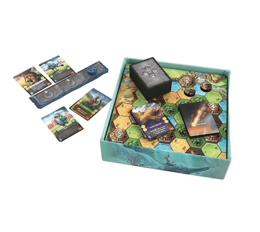 A board game set displayed on a light gray background, featuring a teal illustrated storage box with a colorful hexagonal game board inside, a black dice cube, cards, and blue resource pieces.