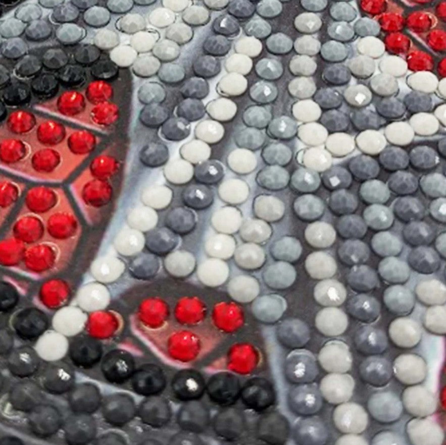 Close-up of a diamond painting or bead art design featuring gray, white, black, and red faceted rhinestones arranged in a pattern.