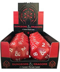 A retail display box filled with red polyhedral Dungeons & Dragons candy dice, with a branded black-and-red header card above. The packaging text reads 'Dungeons & Dragons +1 Cherry Potion Candy.