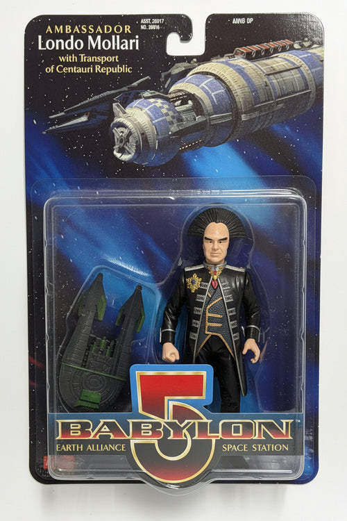 A packaged action figure of Ambassador Londo Mollari from Babylon 5, displayed on a white surface. The figure is dressed in a black coat with gold trim and stands next to a black space station model.