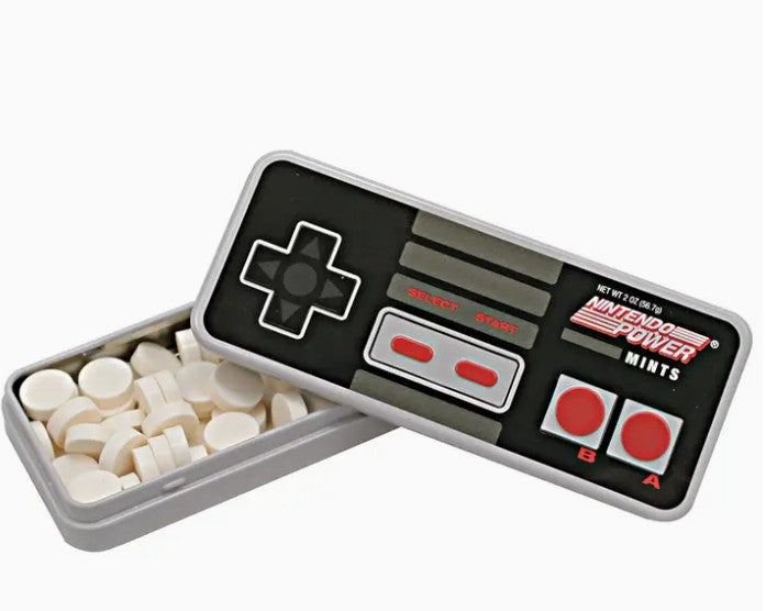 A novelty game controller-shaped tin of mints, with one half open to reveal round white candy pieces inside. The controller face is black with gray buttons and red accents, and the brand text 'Nintendo Power' is visible on the front.