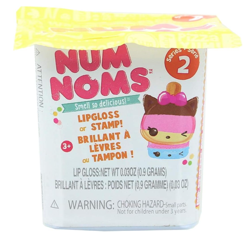 Num Noms Series 2 lip gloss or stamp toy packaging in a clear plastic tub with a white label, featuring a cartoon character and colorful text on a white background.