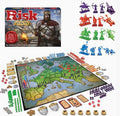 Risk Europe board game set displayed on a white background, showing the game box, the assembled map with player territories, various colored military and resource tokens, dice, and cards. The box features a medieval knight, and the right side shows individual colored unit sets.