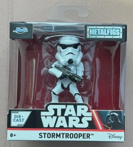 Star Wars Metalfigs Die-Cast Stormtrooper action figure in its original retail packaging, featuring a white stormtrooper holding a blaster against a red background.