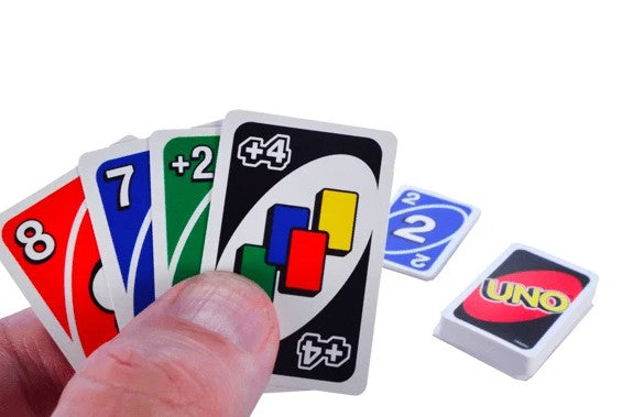 A close-up of a hand holding several UNDO card game cards, with two additional cards and a UNDO box visible on a plain white background.